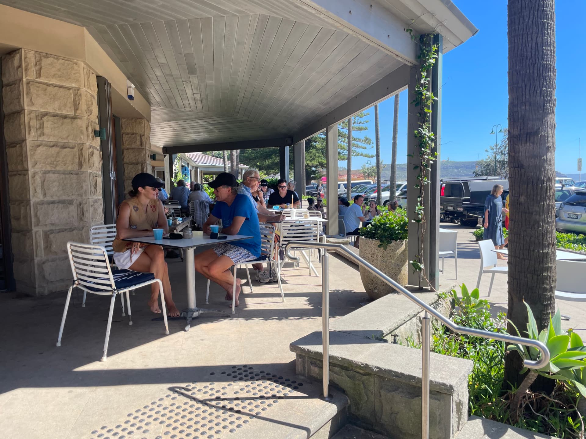 Guests having coffee at outdoor tables under the cafe awning